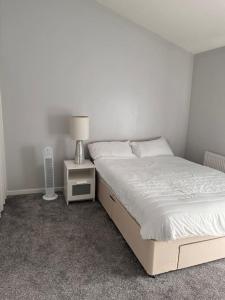 a bedroom with a bed and a night stand with a lamp at Spacious and comfy in Woolwich