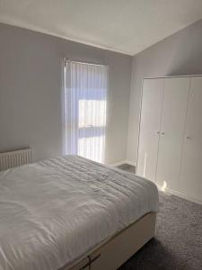 a white bedroom with a bed and a window at Spacious and comfy in Woolwich