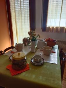 een tafel met een groene tafelkleed met kommen en bekers bij L'angolo di Anna in Pieve di Soligo