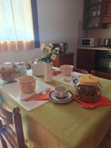 une table avec des assiettes et des tasses et un vase avec des fleurs dans l'établissement L'angolo di Anna, à Pieve di Soligo