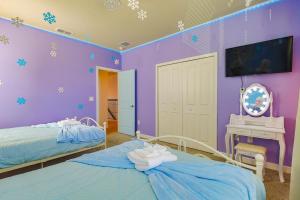 a purple bedroom with two beds and a desk at Thematic Home with Pool Spa and Game room! in Kissimmee
