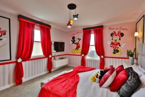 a bedroom with red curtains and a bed with a red comforter at Thematic Home with Pool Spa and Game room! in Kissimmee