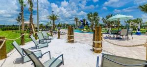 a group of chairs and tables and a pool at Thematic Home with Pool Spa and Game room! in Kissimmee