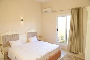 a white bedroom with a bed and a window at Royal Nile Villas - Pool View Apartment 2 in Luxor