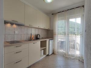 a kitchen with white cabinets and a large window at MM Apartments in Budva