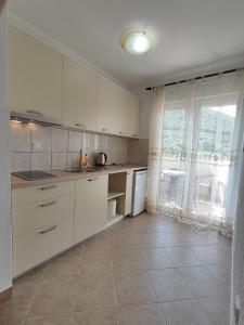 a kitchen with white cabinets and a large window at MM Apartments in Budva