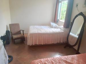 1 dormitorio con cama, espejo y silla en Hostel Leonardo, en Vitória
