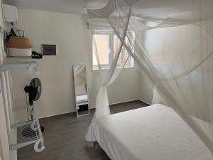1 dormitorio con cama blanca y mosquitera en Cubana Resort Appartement loopafstand Mambo beach, en Willemstad