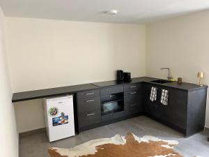 a kitchen with black cabinets and a white refrigerator at Cubana Resort Appartement loopafstand Mambo beach in Willemstad