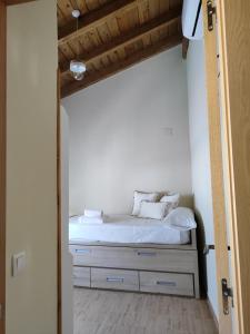 a bed with white sheets and pillows in a room at La casita de Ra in Castillo de Bayuela