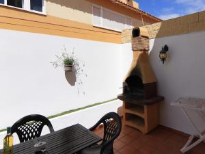 eine Terrasse mit einem Holzkohlegrill an der Seite eines Gebäudes in der Unterkunft Casa Vazquez in Costa Del Silencio