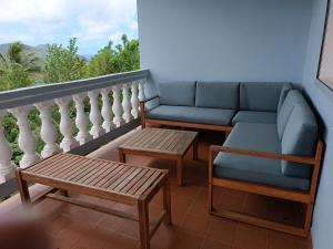 balcón con sofá, mesa y banco en corossol, en Rivière-Pilote