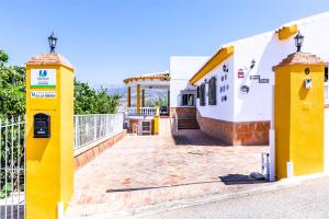 a house with two yellow columns in front of it at CASA RURAL VILLAMAYNO in Alcaucín