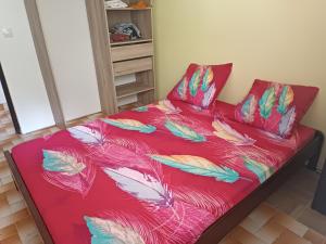 una cama roja con plumas en una habitación en corossol, en Rivière-Pilote
