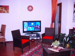 uma sala de estar com uma televisão de ecrã plano e cadeiras em SEGESTA Nouveau Bedding em Salemi