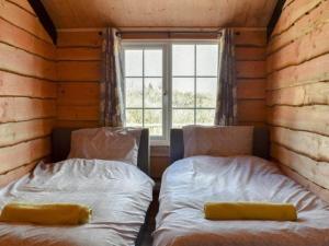 two beds in a room with a window at Brook Lodge in Liskeard