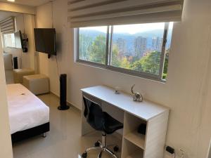 - une chambre avec un bureau, un lit et une fenêtre dans l'établissement Apartasuite moderna - en el corazón del poblado medellín, à Medellín