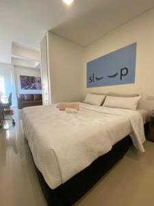 - un grand lit dans une chambre dotée d'un grand couvre-lit blanc dans l'établissement Apartasuite moderna - en el corazón del poblado medellín, à Medellín