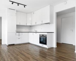 uma cozinha branca com armários brancos e piso em madeira em Family-Friendly Apartment close to the beach em Rød