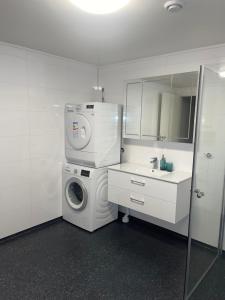 uma casa de banho branca com uma máquina de lavar roupa e um lavatório em Family-Friendly Apartment close to the beach em Rød