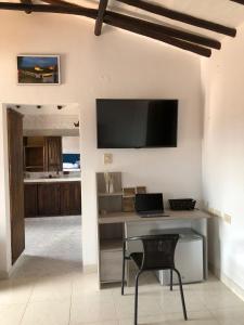 sala de estar con escritorio y TV en la pared en Rustico Hostel Barichara, en Barichara