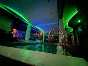 een zwembad in een gebouw met groene lichten bij Hotel Rosa Blu in Tirana