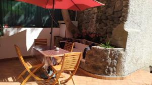 a table and chairs with a red umbrella on a patio at Casetta Emilia vicino al mare in Ischia
