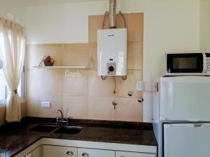 a kitchen with a sink and a white refrigerator at Cabañas Teodoro in Tanti