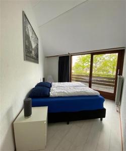 ein Schlafzimmer mit einem blauen Bett und einem Fenster in der Unterkunft De Vlinder in Brouwershaven