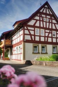 una casa con un edificio rojo y blanco con flores rosas en Ferienwohnung Vorndran en Bischofsheim an der Rhön