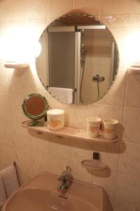 ein Waschbecken mit Spiegel und drei Tassen im Regal in der Unterkunft Ferienwohnung Vorndran in Bischofsheim an der Rhön