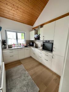 cocina con armarios blancos y techo de madera en Wiehler- Ferienwohnung, en Wiehl