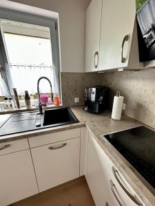 eine Küche mit weißen Schränken, einem Waschbecken und einem Fenster in der Unterkunft Wiehler- Ferienwohnung in Wiehl