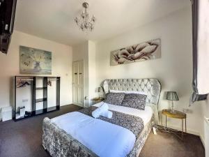 ein Schlafzimmer mit einem großen Bett und einem Kronleuchter in der Unterkunft Luxury and lovely Cosy well equipped home with Free Parking and Free Fast WiFi in Morley