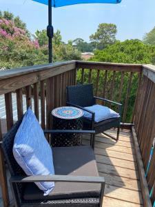 a deck with two chairs and a table and an umbrella at Pelican Nest-Heated Pool Jacuzzi Tub Pvt Balcony in Pensacola