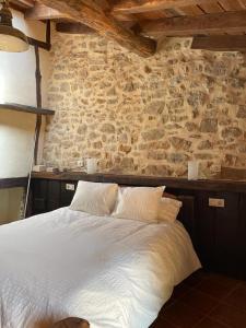 um quarto com uma cama branca e uma parede de pedra em LA CASA DEL HORNO em Hornedo