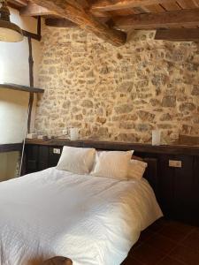 a bedroom with a white bed with a stone wall at LA CASA DEL HORNO in Hornedo +20 photos