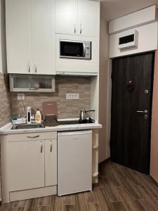 a kitchen with white cabinets and a black door at Squeeze The Day in Belgrade +3 photos