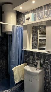 a bathroom with a sink and a blue shower curtain at Squeeze The Day in Belgrade
