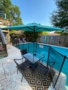a table and chairs under an umbrella next to a swimming pool at Pelican Nest-Heated Pool Jacuzzi Tub Pvt Balcony in Pensacola