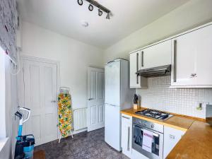 cocina con armarios blancos y nevera blanca en Luxury and lovely Cosy well equipped home with Free Parking and Free Fast WiFi en Morley