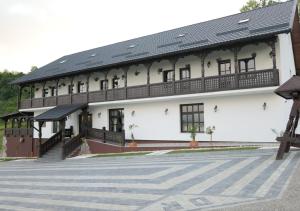 a large white building with a black roof at Mosia Dar In Rai in Berbeşti