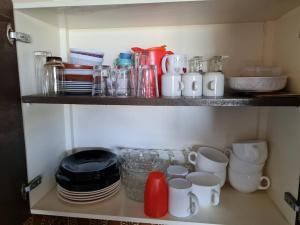 a shelf with cups and plates and mugs on it at Belle vue au château d'Ancelle in Ancelle