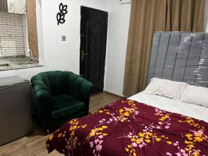 a bedroom with a bed and a green chair at The Casterwells in Ibadan