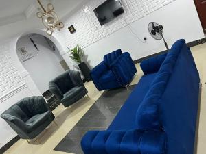 sala de estar con sofá azul y sillas en The Casterwells, en Ibadán