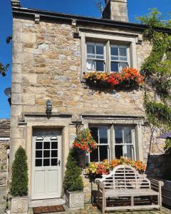 une maison en pierre avec deux bancs devant elle dans l'établissement The Lower Buck Inn, à Clitheroe