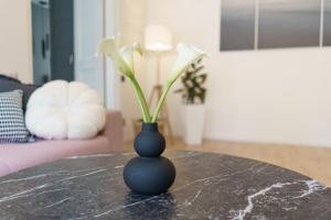 a black vase sitting on a table with flowers at Centra apartamenti in Liepāja