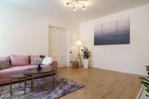 een woonkamer met een roze bank en een tafel bij Centra apartamenti in Liepāja