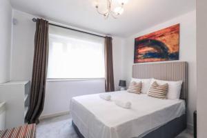 a white bedroom with a large window and a bed at Glamorous Central Apartment in London