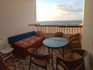 balcón con sofá, mesa y sillas en Furnished Apartment - Beach view "Nearest Beach 2 minutes walking" - Free Wifi- Abo keer - Alexandria - Egypt, en Abū Qīr
